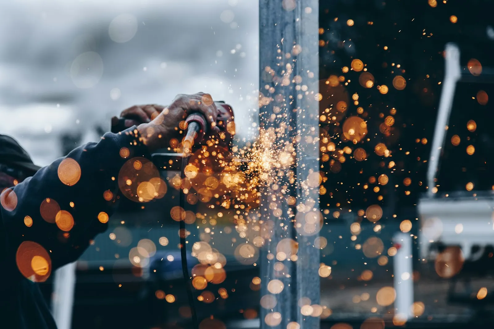 Fabricator grinding a steel component, sparks flying