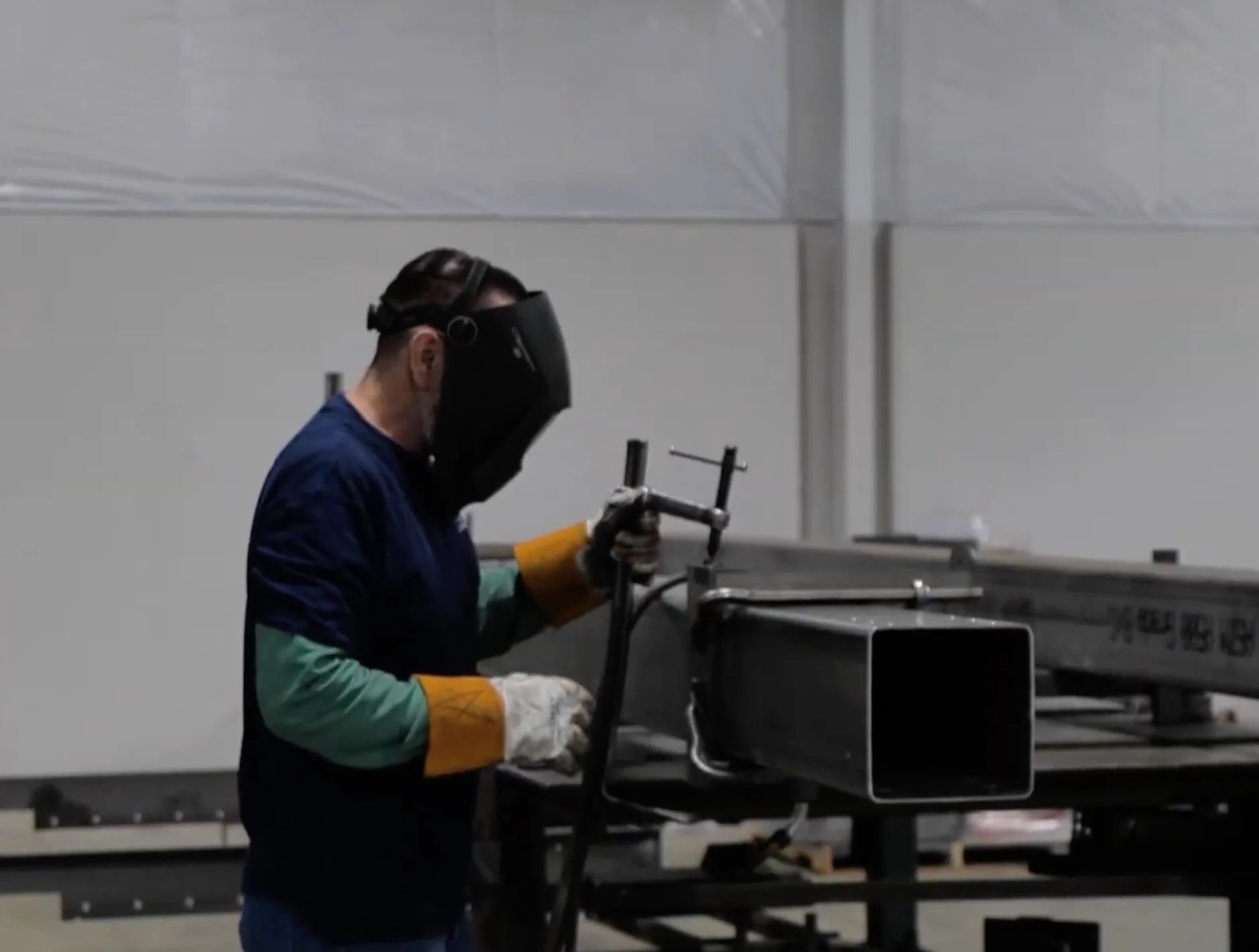 Fabricator clamping a square steel tube in the shop