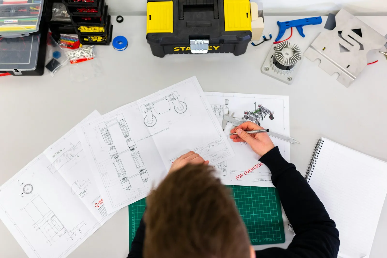 Engineer drafting a conveyor layout over plant drawings